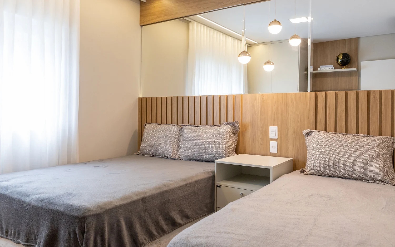 Quarto com duas camas e cabeceira em madeira